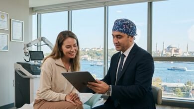 استشارة طبية داخل عيادة تجميل حديثة في إسطنبول؛ يظهر طبيب متخصص يشرح خطة العلاج لمريض أجنبي باستخدام تقنيات رقمية، مع إطلالة زجاجية على المدينة، مما يرمز لتطور السياحة العلاجية في تركيا 2026.