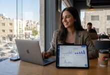 رائدة أعمال أردنية تحلل بيانات التسويق عبر منصات التواصل والمبيعات بالدينار الأردني على لوحة تحكم رقمية في جلسة على سطح بعمان لعام 2026.